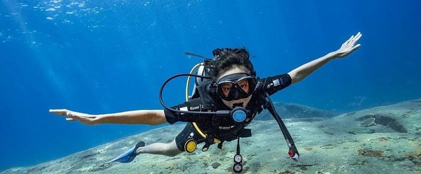 Instructor pointing out marine life to a student underwater.
